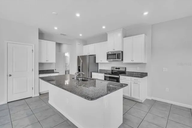 a kitchen with stainless steel appliances granite countertop a sink a stove a microwave and a refrigerator