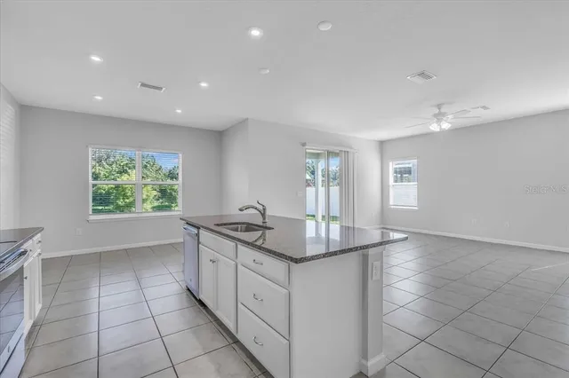a kitchen with stainless steel appliances granite countertop a sink and a white cabinets