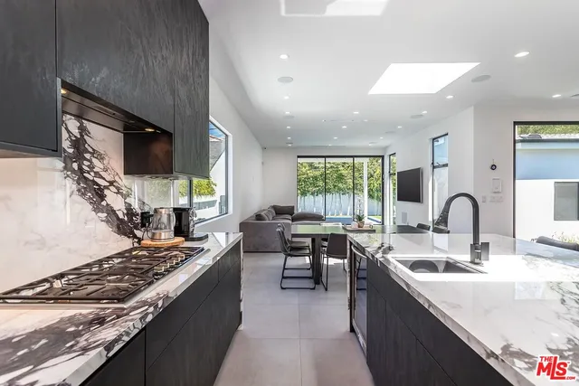 a kitchen with kitchen island granite countertop a sink stove and cabinets