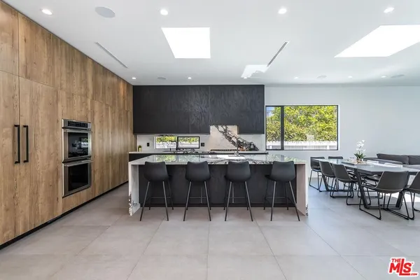 a kitchen with stainless steel appliances kitchen island granite countertop a table chairs sink and cabinets