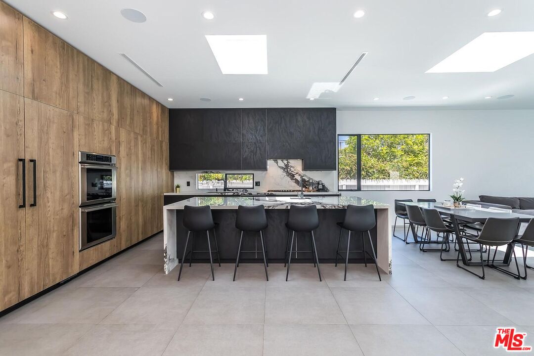 1948 South Point View Street Los Angeles, CA 90034 - Photo 10 of 27 a kitchen with stainless steel appliances kitchen island granite countertop a table chairs sink and cabinets