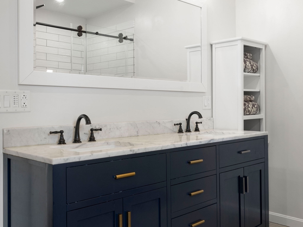 299 Central Avenue Dedham, MA 02026 - Photo 27 of 39 a bathroom with a granite countertop sink a mirror and shower