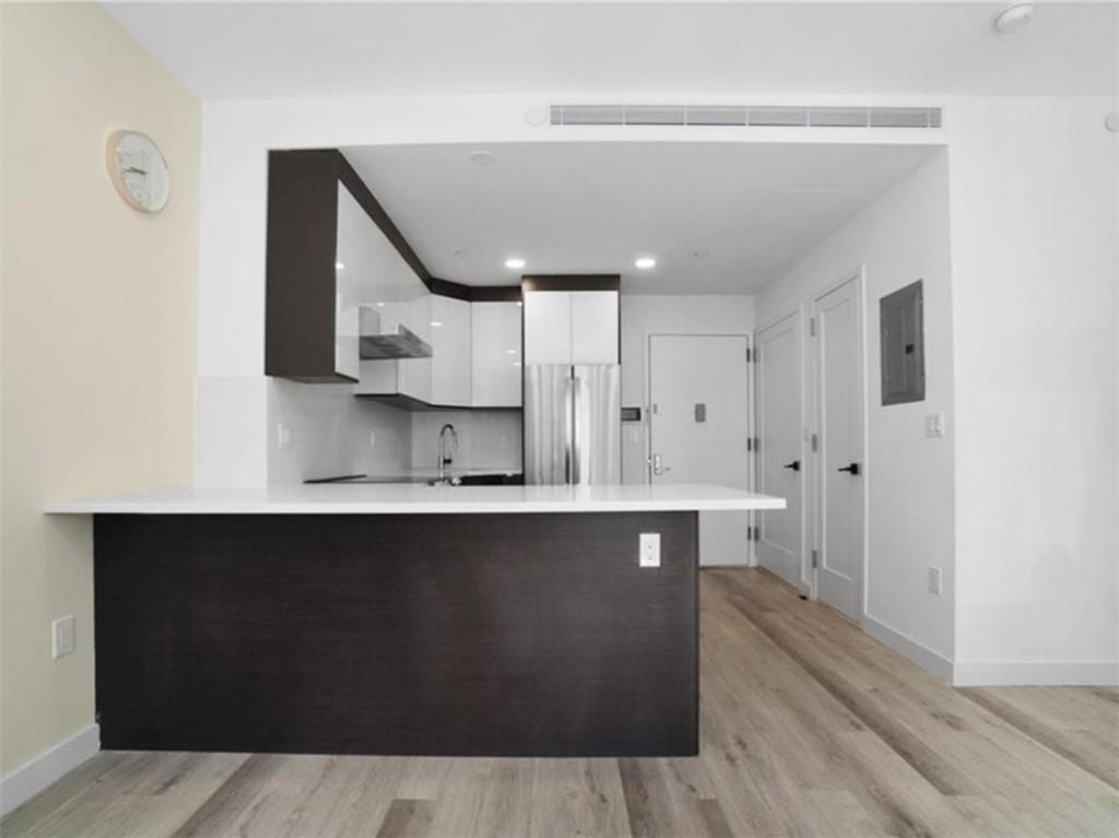 1238 63rd Street, Unit 326 Brooklyn, NY 11219 - Photo 2 of 5 a large kitchen with stainless steel appliances a sink and cabinets