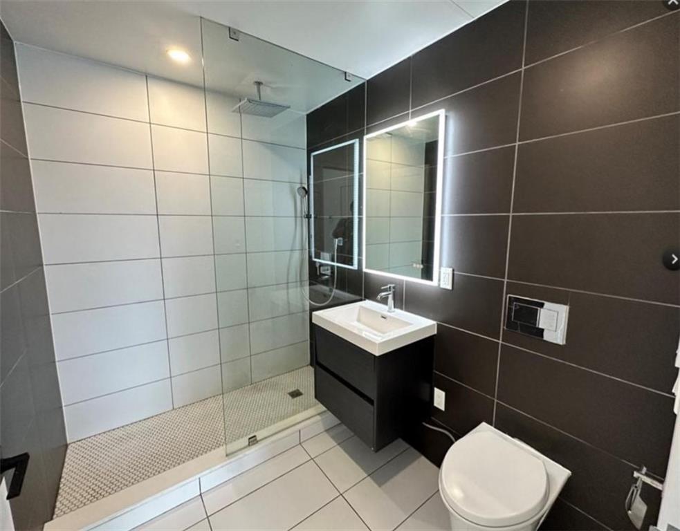 1238 63rd Street, Unit 326 Brooklyn, NY 11219 - Photo 4 of 5 a bathroom with a toilet a sink and shower