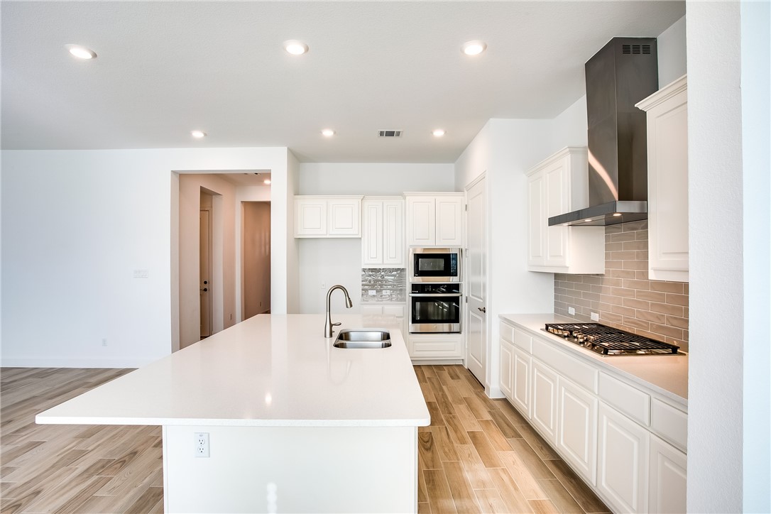 505 Affazia Lane Georgetown, TX 78628 - Photo 11 of 32 a kitchen with kitchen island stainless steel appliances a sink and a stove