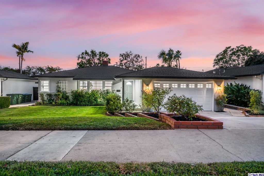 a front view of a house with a yard and a garden