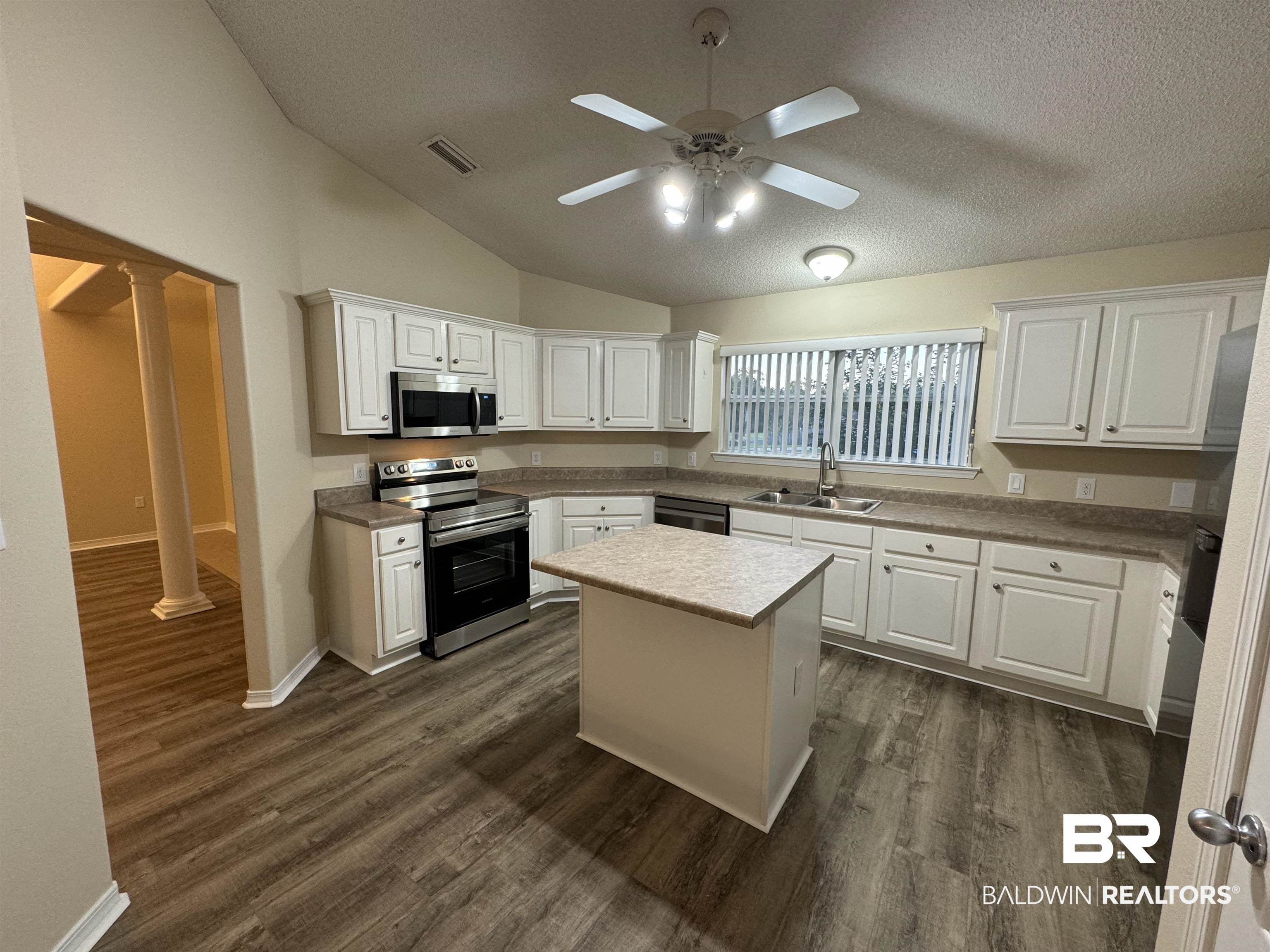 32769 Arbor Ridge Circle Lillian, AL 36549 - Photo 6 of 36 Kitchen featuring a kitchen island, vaulted ceiling, sink, stainless steel appliances, and white cabinets