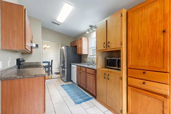 a kitchen with stainless steel appliances granite countertop a refrigerator a stove and a sink