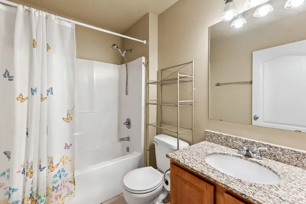 a bathroom with a granite countertop sink toilet mirror and shower