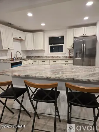 a kitchen with stainless steel appliances granite countertop a stove top oven a sink a refrigerator white cabinets and wooden floor