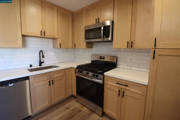 a kitchen with stainless steel appliances granite countertop a stove a sink and a microwave