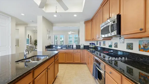 a kitchen with kitchen island granite countertop a sink counter top space appliances and cabinets