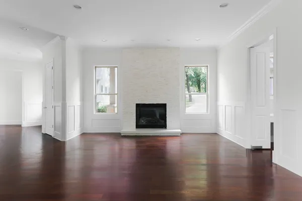 a view of an empty room with wooden floor and a window