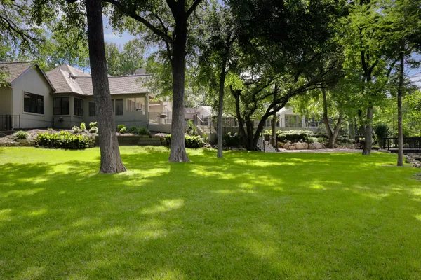 a front view of a house with garden and trees