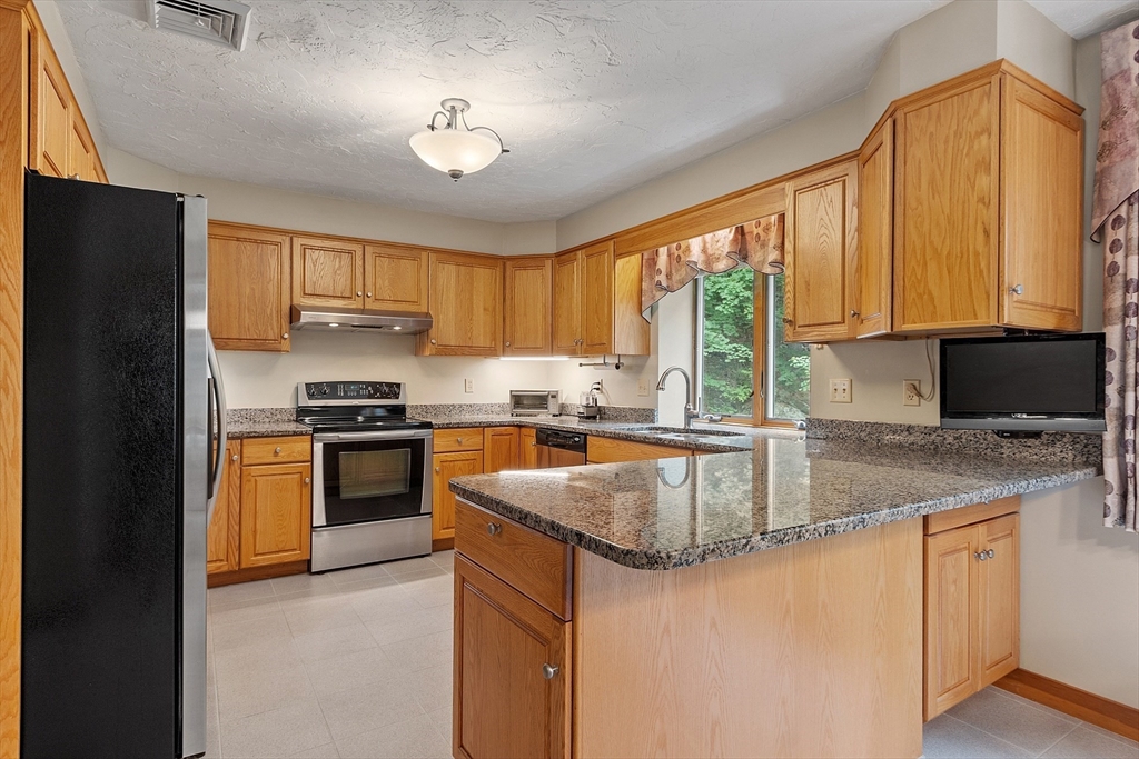 624 Old Harvard Road Boxborough, MA 01719 - Photo 9 of 42 a kitchen with granite countertop a stove a sink a refrigerator and blue cabinets with wooden floor