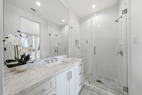 a bathroom with a granite countertop sink a mirror and a shower