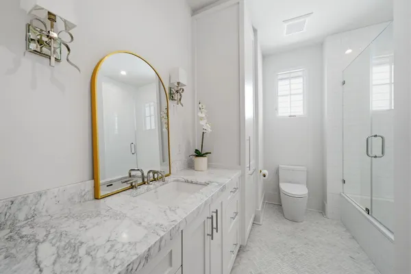 a bathroom with a granite countertop sink mirror and toilet