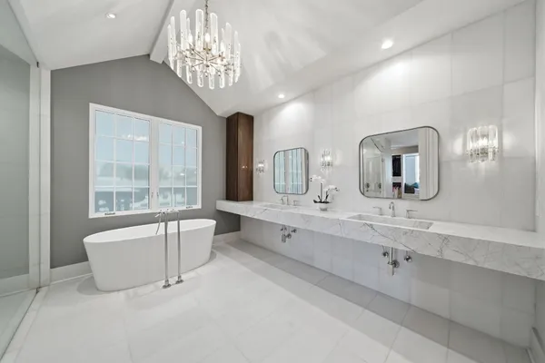 a spacious bathroom with a double vanity sink a large mirror and a bathtub
