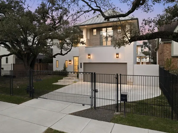 a view of a house with a small yard and a large tree