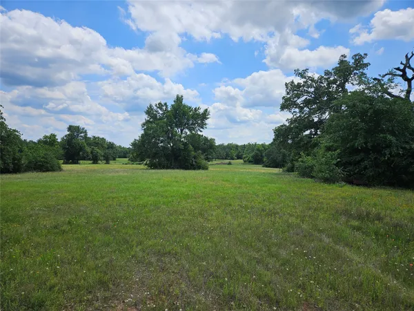a view of a green field with wooden fence