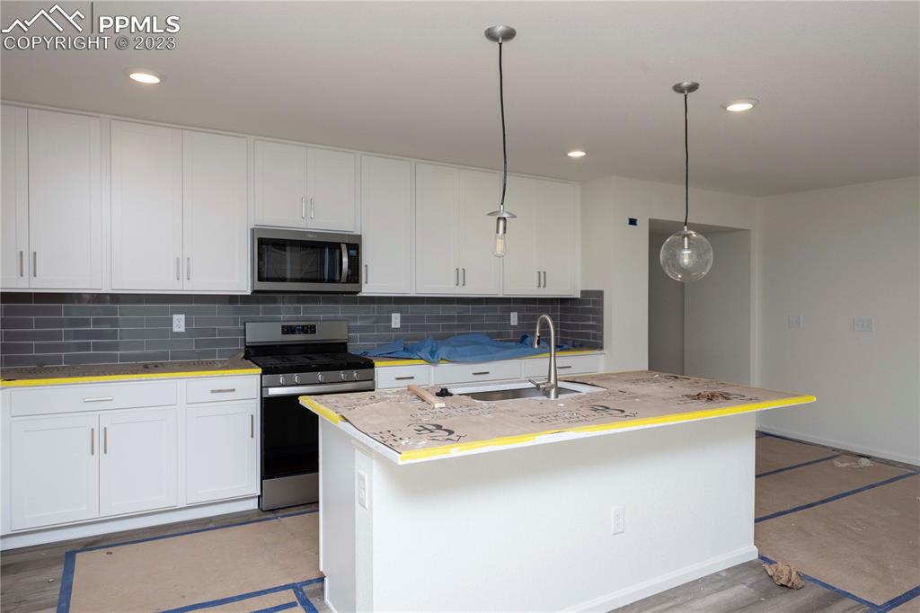 644 Felicity Loop Castle Rock, CO 80109 - Photo 8 of 23 a kitchen with kitchen island white cabinets appliances and a sink
