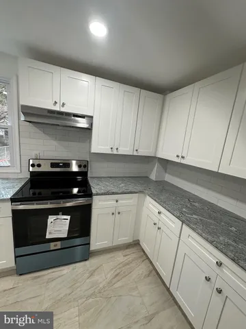 a kitchen with granite countertop a stove sink and cabinets