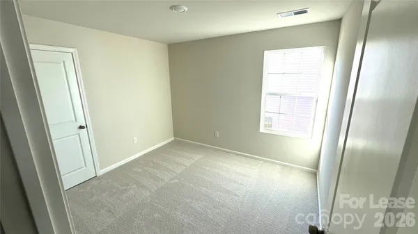 a view of an empty room with wooden floor and a mirror