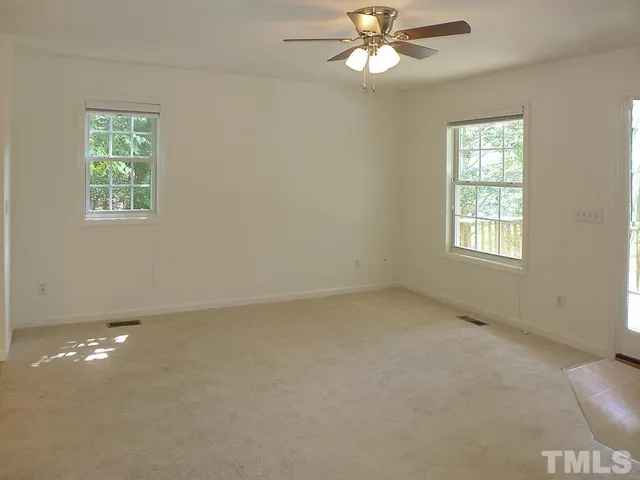 an empty room with windows and fan