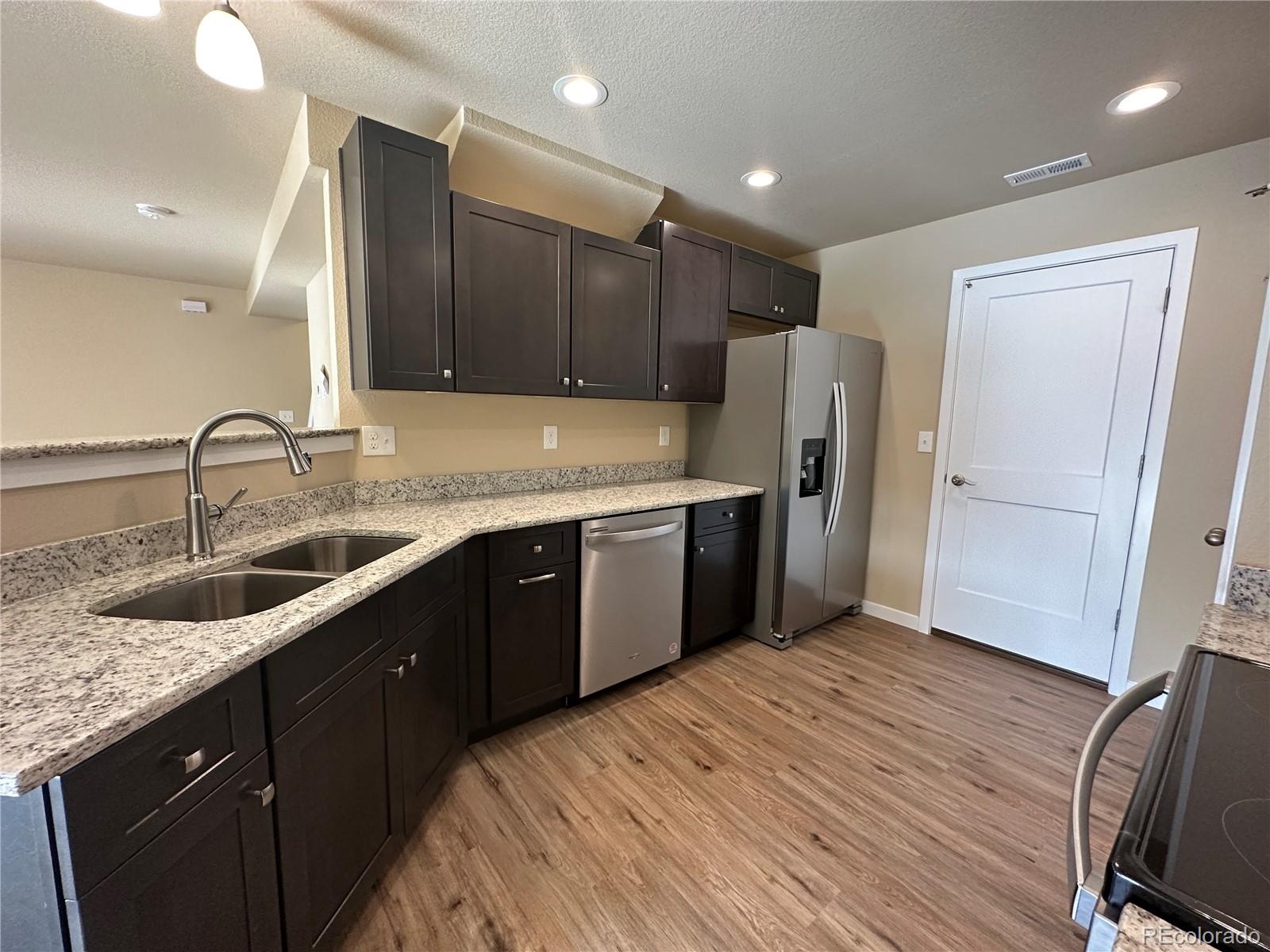 4213 Date Street Colorado Springs, CO 80917 - Photo 5 of 20 a kitchen with a sink a refrigerator and wooden cabinets