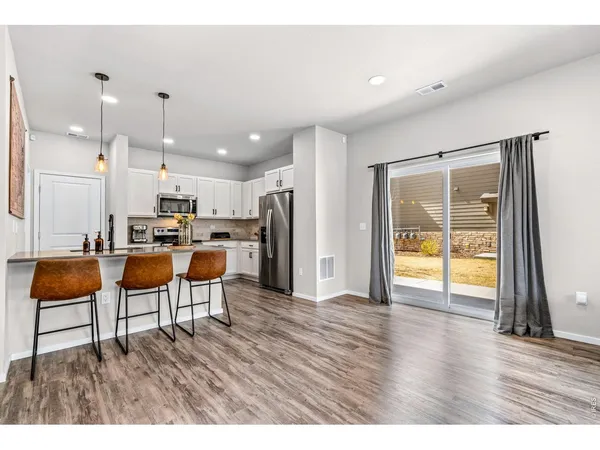 a living room with kitchen view and a refrigerator with wooden floor
