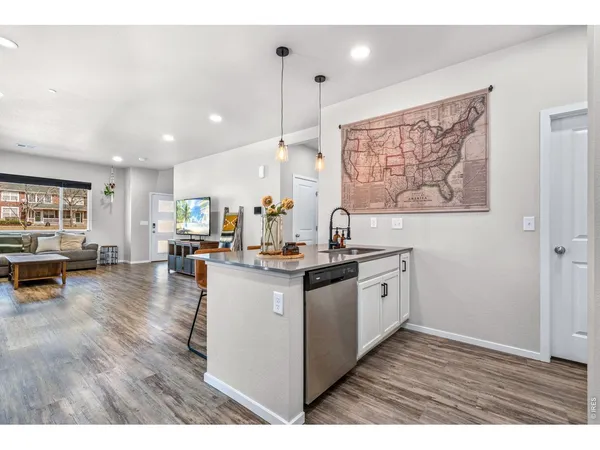 a kitchen with granite countertop a stove top oven a sink a dining table and chairs with wooden floor