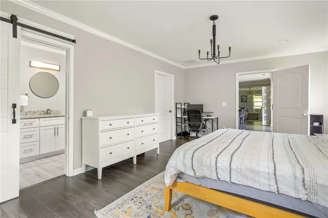 a bedroom with a bed a chandelier and a dresser