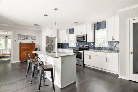 a kitchen with granite countertop white cabinets and refrigerator