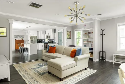 a living room with furniture kitchen view and a chandelier