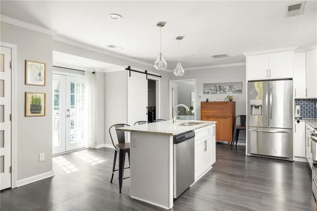 a kitchen with a refrigerator a sink dishwasher a stove and a dining table with wooden floor