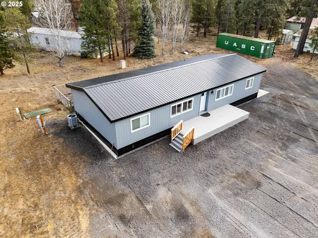 a aerial view of a house with yard and trees in the background