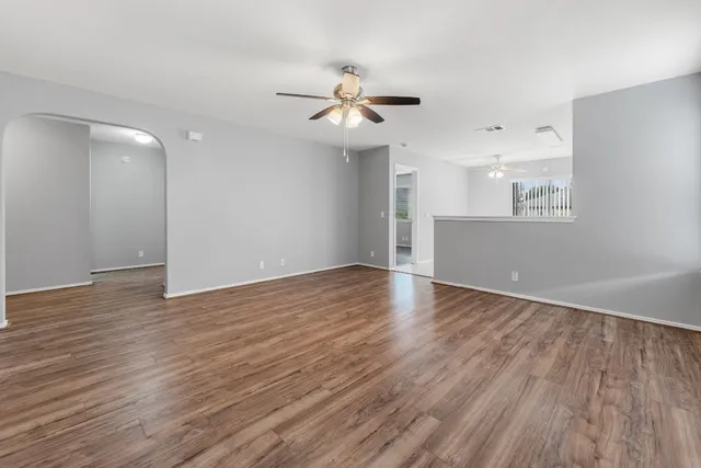 an empty room with wooden floor and windows