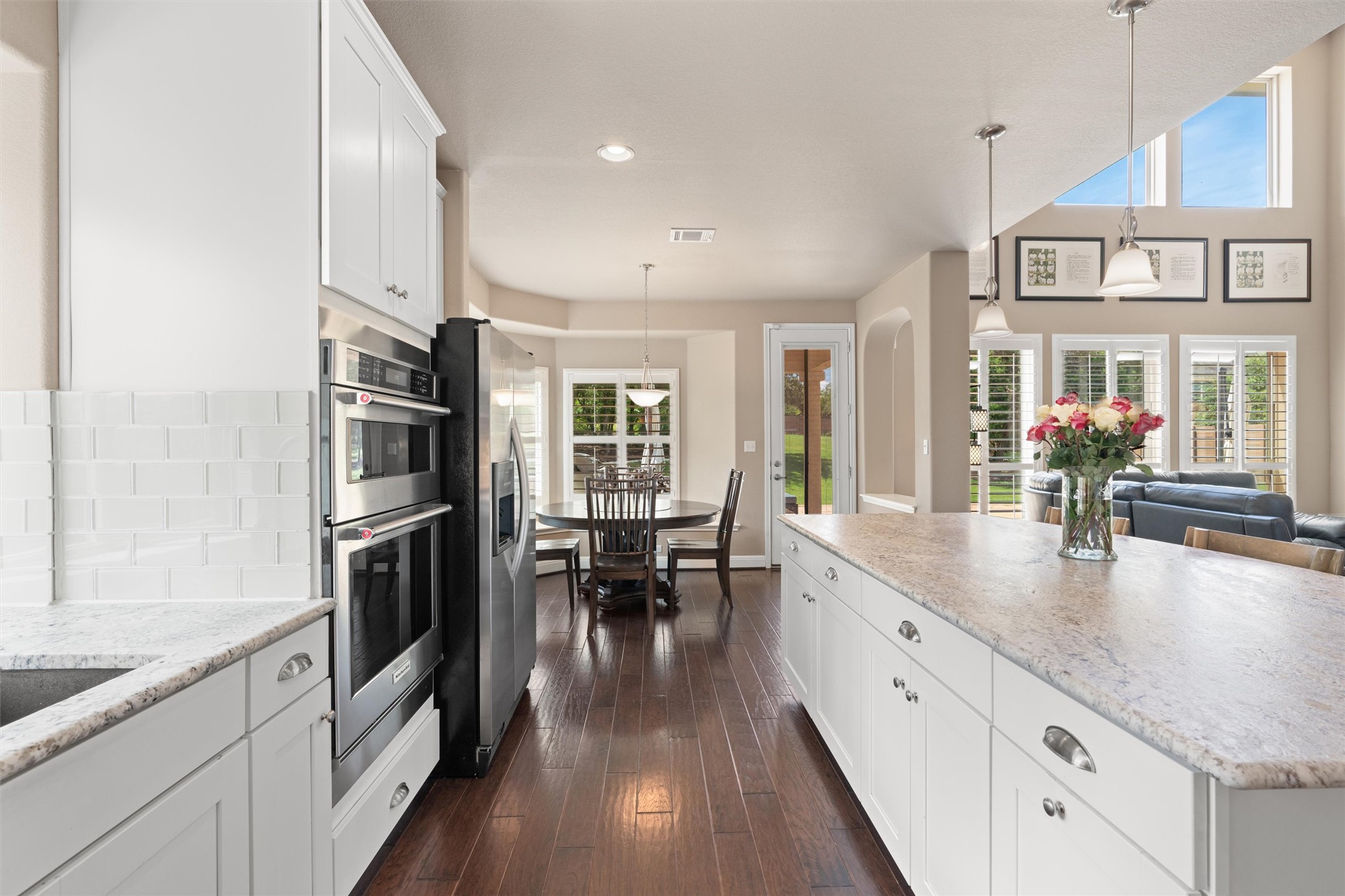 7716 Aria Loop Austin, TX 78736 - Photo 12 of 39 An inviting open-concept kitchen features rich wood flooring, gleaming stainless steel appliances, and a generously sized island with granite countertops.