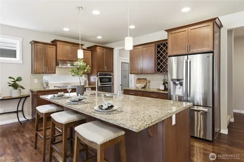a kitchen with stainless steel appliances granite countertop a table chairs refrigerator and microwave