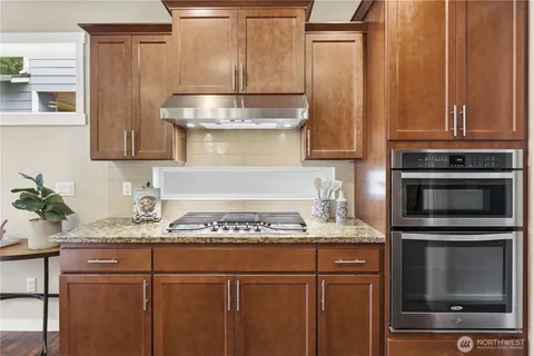 a kitchen with granite countertop stainless steel appliances wooden cabinets and a counter top