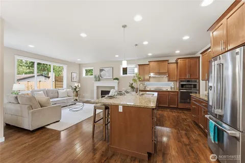 a living room with stainless steel appliances granite countertop furniture wooden floor and a view of kitchen
