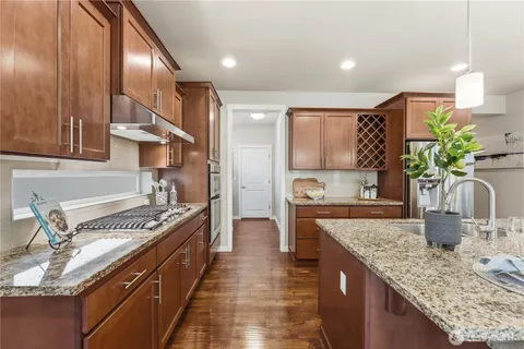 a kitchen with stainless steel appliances granite countertop a sink stove and cabinets
