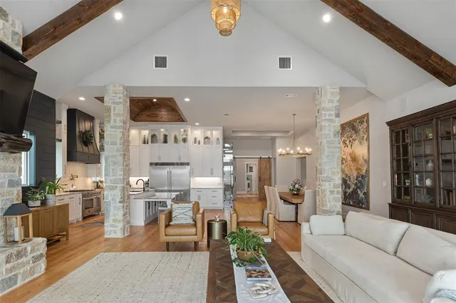 a living room with couches and kitchen view with wooden floor