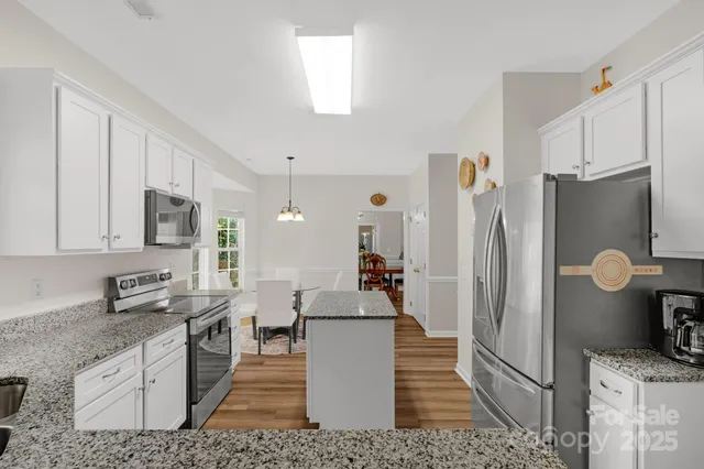 a kitchen with stainless steel appliances granite countertop a refrigerator a stove and a sink
