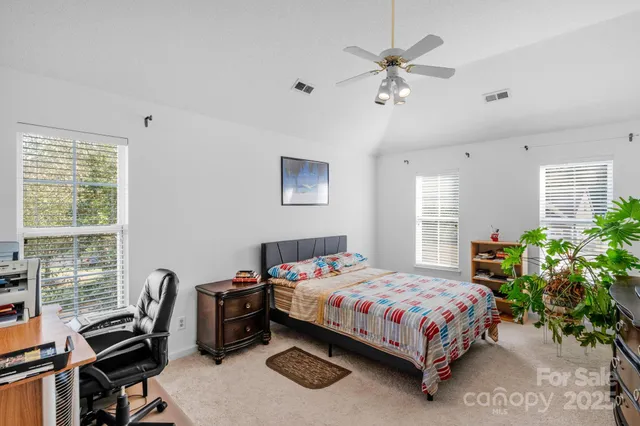 a bedroom with a bed table chair and a window