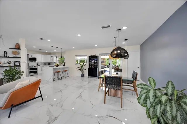 a living room with furniture a chandelier and kitchen view