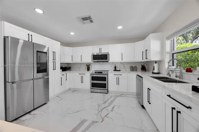 a kitchen with granite countertop white cabinets and stainless steel appliances