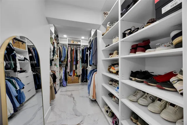 a view of walk in closet with clothes and shoes