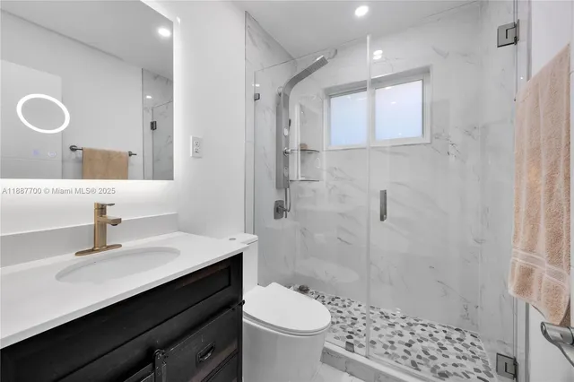 a bathroom with a sink a toilet a shower and a mirror