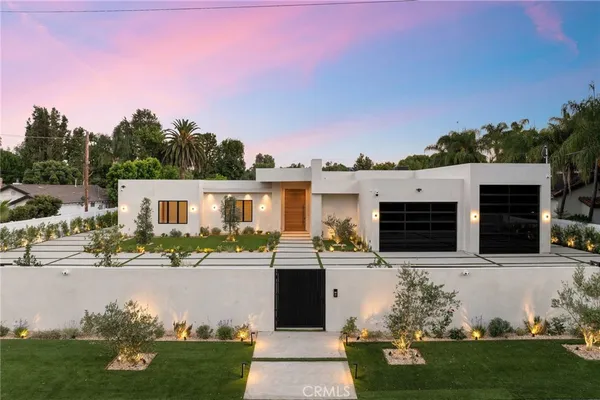 a front view of a house with a yard and potted plants